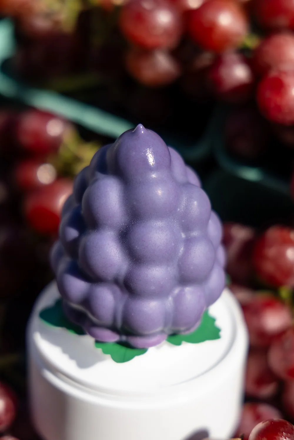 Purple fruit-shaped novelty ice cream displayed among fresh fruit